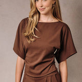 Cocoa brown top with wide boat neckline, kimono sleeves, and ruched waist worn by a model.
