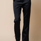 Black satin pants with beaded detailing at the ankles and functional side pockets.