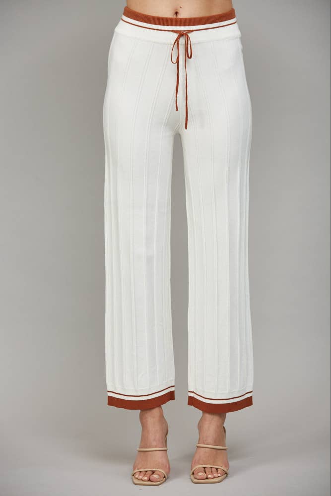 White ribbed knit pants with cognac trim at the waistband and hem, featuring a drawstring waist.