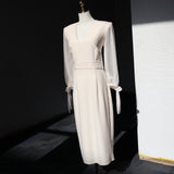 Ivory Reverie Midi Dress in white with V-neckline and long chiffon sleeves displayed on a mannequin.