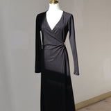 Black wrap midi dress with a V-neckline, long sleeves, and gold-tone waist accent displayed on a mannequin.